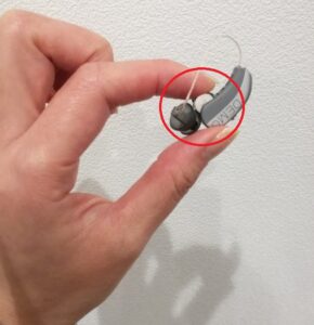 補聴器から電池を取り出して見せている画像。親指と人差指で挟んで持っていて電池が非常に小さいことがわかる画像です